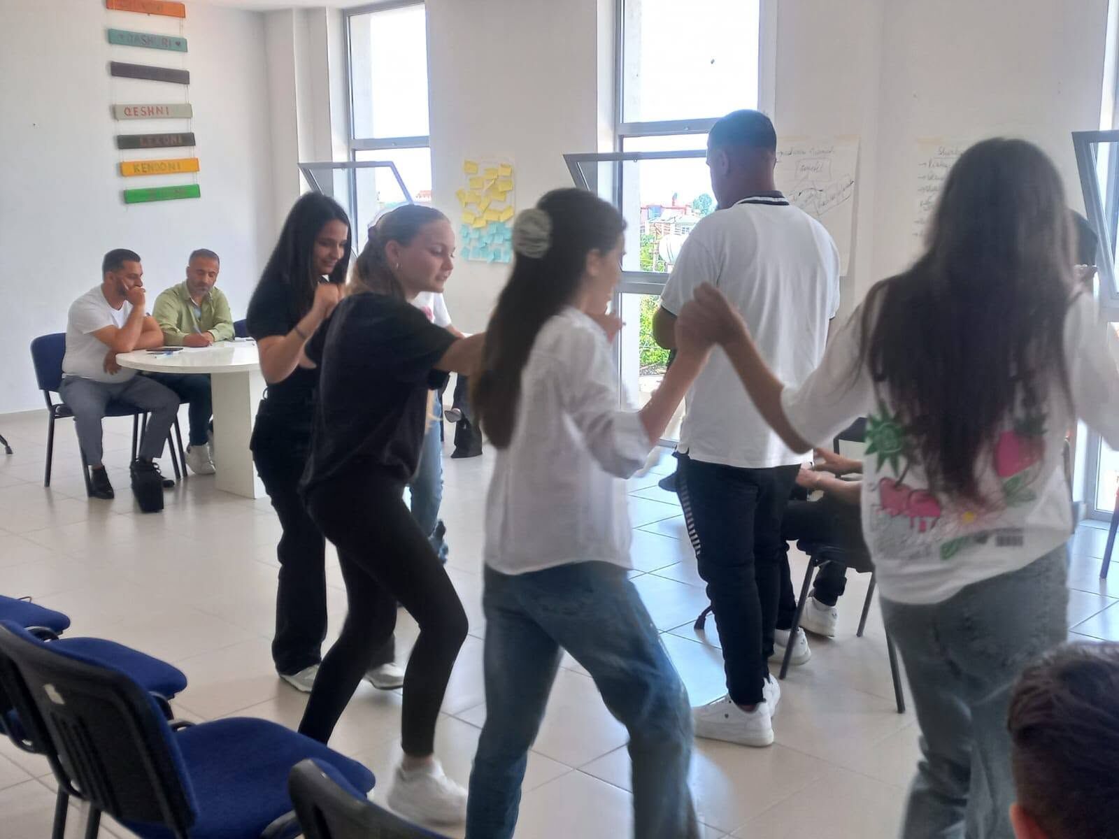 Të rinj që kërcejnë një valle tradicionale në një sallë komunitare
